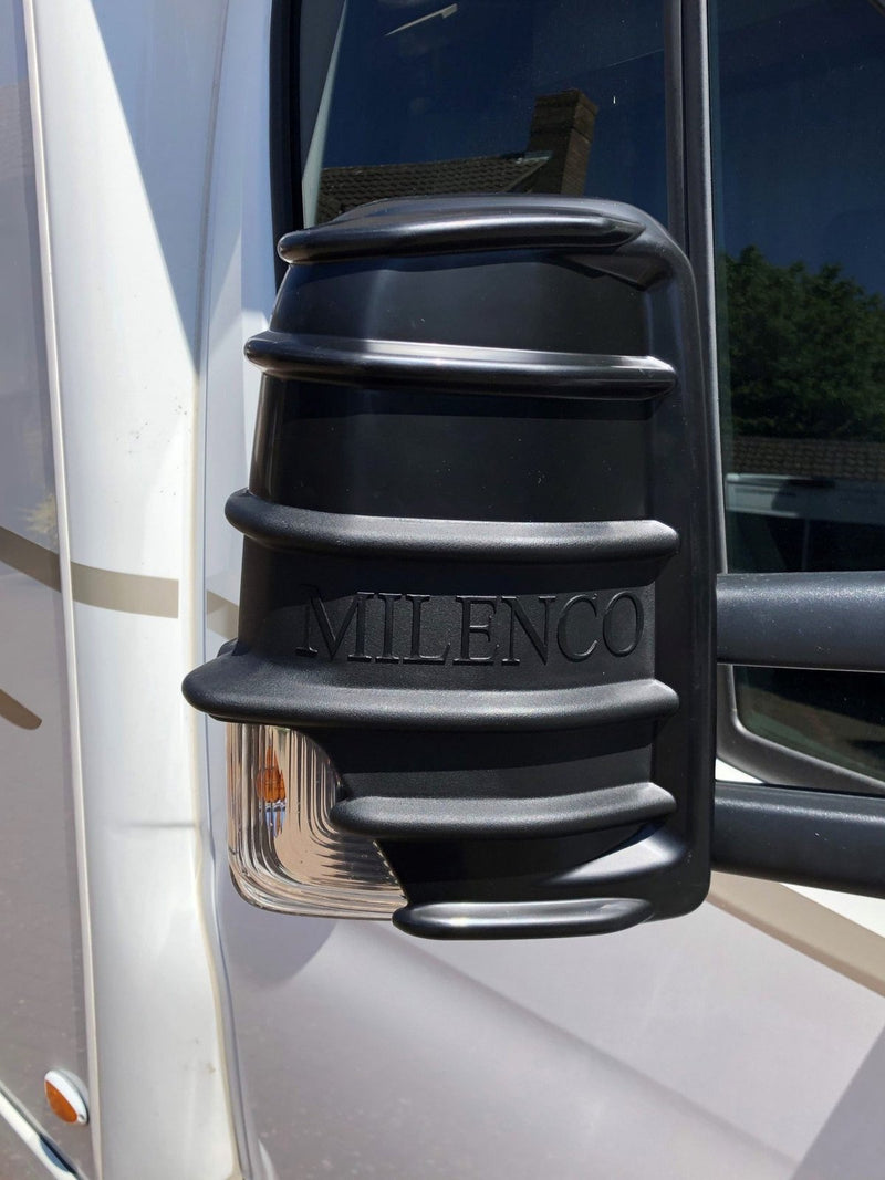 Black Milenco mirror protector fitted to a motorhome cab mirror, close-up with embossed logo