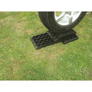 Milenco Stacka Level 3 stacked under a car wheel on grass, with Tyre Saver top