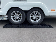 Milenco Stacka Levels stacked under a caravan's twin axle wheels on a driveway
