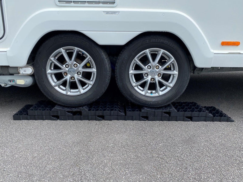 Milenco Stacka Levels stacked under a caravan's twin axle wheels on a driveway