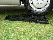 Milenco Stacka Level blocks stacked into a ramp under a caravan tyre on grass